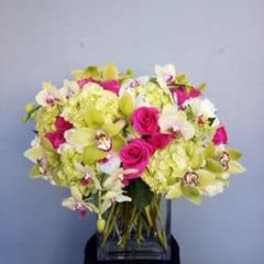 Bouquet of pink roses and pale green orchids in a clear vase