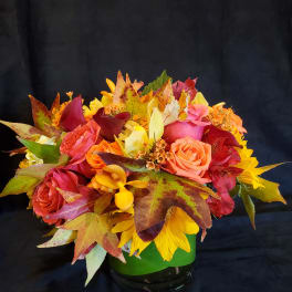 Autumn bouquet of roses, calla lilies, and sunflowers in a green vase