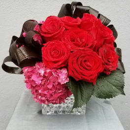 Red roses and pink hydrangeas in a clear square vase