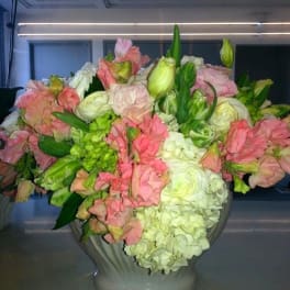 Large pastel floral arrangement in a gray urn vase