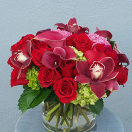 Red roses and burgundy calla lilies in a clear glass vase