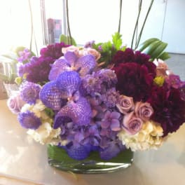 Purple and lavender floral arrangement in a glass vase