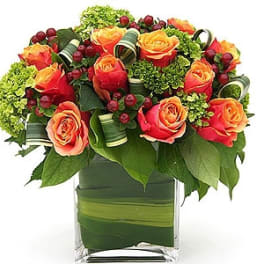 Orange and pink roses in a square glass vase