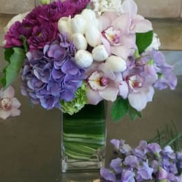 Purple and white flowers arranged in a tall glass vase