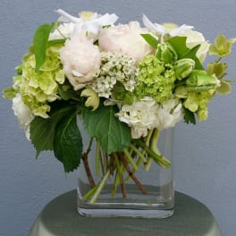 White and pale green floral arrangement in a clear glass vase