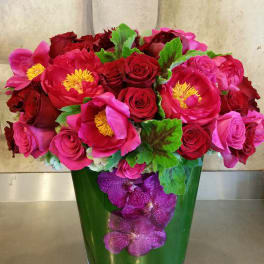 Pink and red flower arrangement in a green glass vase