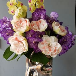 Bouquet of yellow and purple orchids in a silver vase