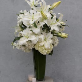White lilies and hydrangeas arranged in a tall glass vase
