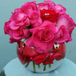 Pink and red roses arranged in a round glass vase