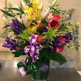 Colorful orchid and lily arrangement in a clear glass vase