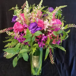 Bouquet of pink and purple flowers in a tall glass vase