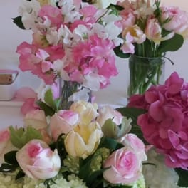 Pink and white floral arrangements with roses and hydrangeas in glass vases