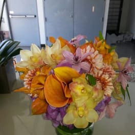 Bouquet of orange, yellow, pink, and purple flowers in a glass vase