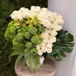 Large arrangement of white roses and green blooms in a white pot
