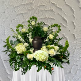 White floral funeral arrangement with a dark urn centerpiece
