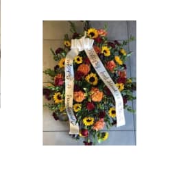 Standing floral spray with sunflowers and roses, finished with white ribbons