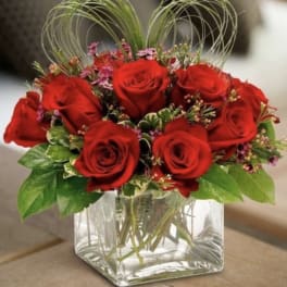 Red roses arranged in a clear square glass vase