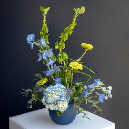 Blue and yellow floral arrangement in a blue vase