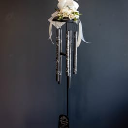 White floral topper with ribbon on a black wind chime stand