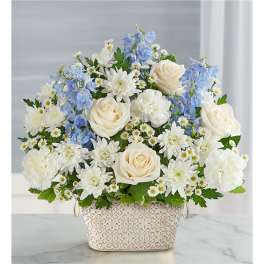 White roses and blue flowers arranged in a patterned basket