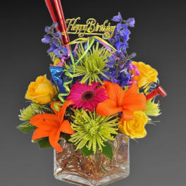Colorful birthday flower arrangement in a clear square vase