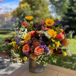 Colorful mixed bouquet in a metal vase on a wooden table