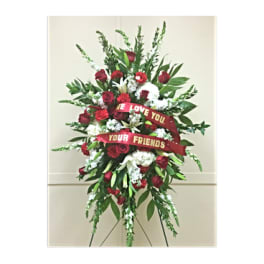 Standing floral spray with red roses and white flowers on an easel