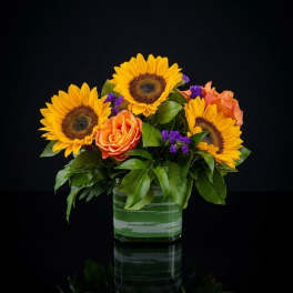 Sunflowers and orange roses arranged in a glass vase