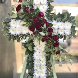 Cross-shaped floral tribute with white daisies and burgundy roses