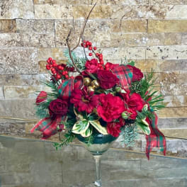 Red floral arrangement in a wine glass vase with plaid ribbon