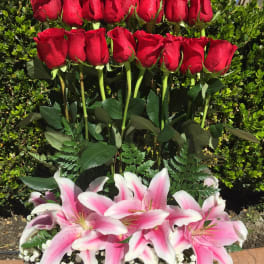 Red roses above pink-and-white lilies in a glass vase
