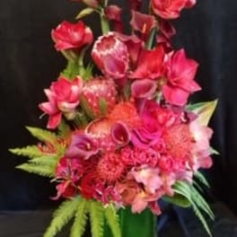 Tall pink and red floral arrangement in a green vase