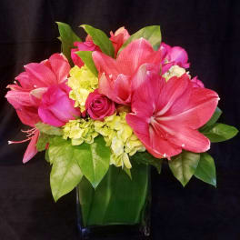 Pink and coral flowers arranged in a square glass vase
