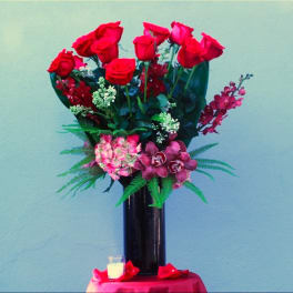 Tall bouquet of red roses and pink orchids in a black vase