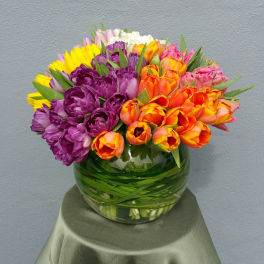 Colorful tulip bouquet in a round glass vase