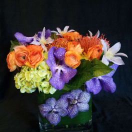 Colorful bouquet in a clear glass vase with orange, purple, and white blooms