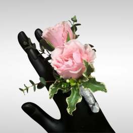 Small pink rose corsage with silver-wrapped stems displayed on a black mannequin hand