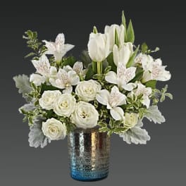 White roses and tulips arranged in a blue glass vase