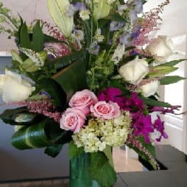 Tall mixed bouquet in a glass vase with pink, white, and purple flowers