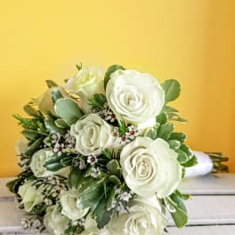 Bouquet of white roses with greenery on a yellow background
