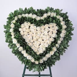 Heart-shaped floral wreath of white roses on a stand