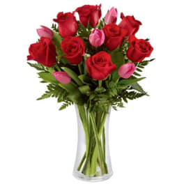 Red roses and pink tulips in a clear glass vase