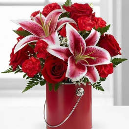 Red roses and pink lilies in a red metal bucket