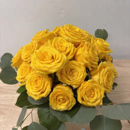 Bouquet of yellow roses with eucalyptus on a wooden surface