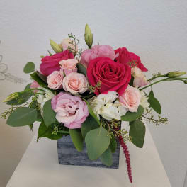 Pink and white rose arrangement in a square gray vase