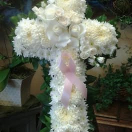 White floral cross arrangement with a pink ribbon