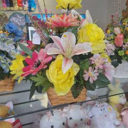 Mixed bouquet in a woven basket with yellow, pink, and white flowers