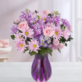 Pink and purple mixed bouquet in a purple glass vase