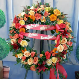 Large floral funeral wreath with roses and ribbons on an easel