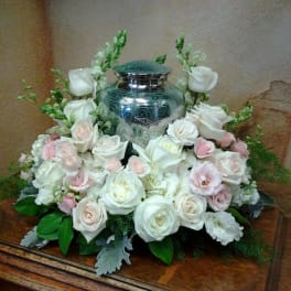 White and blush roses arranged around a silver urn